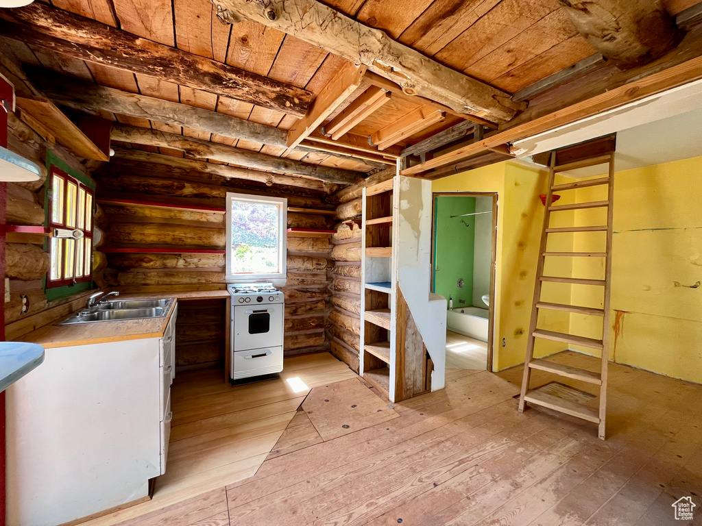Kitchen with light wood-type flooring, log walls, gas range gas stove, sink, and wood ceiling