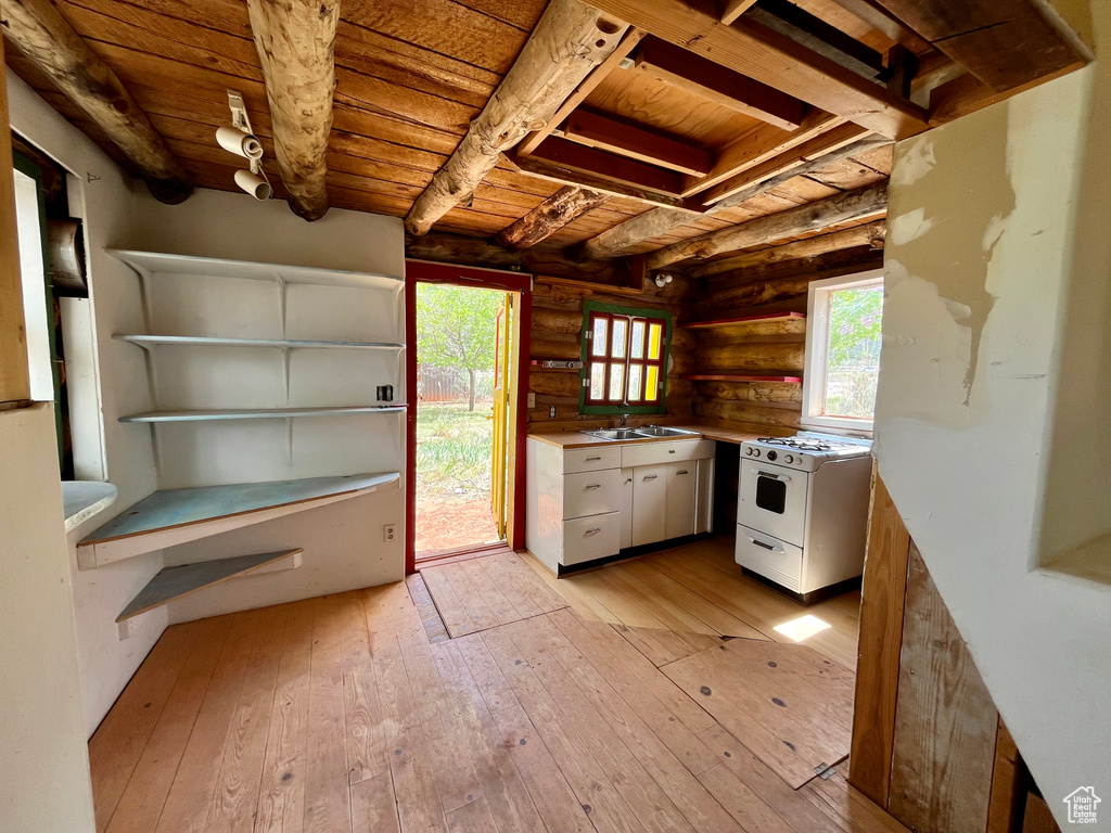 Kitchen with log walls, wooden ceiling, light wood-type flooring, and white gas stove