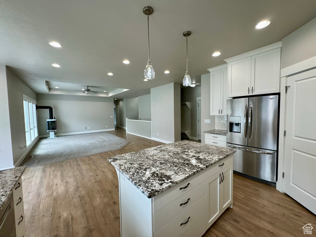 Kitchen with white cabinets, a kitchen island, wood-type flooring, ceiling fan, and stainless steel refrigerator with ice dispenser