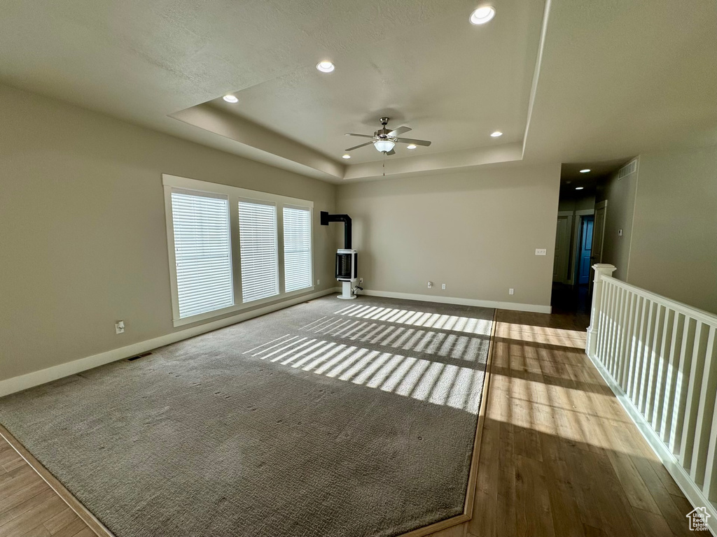 Empty room featuring a raised ceiling, ceiling fan, and light hardwood / wood-style floors