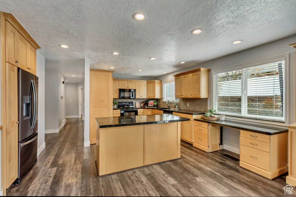 Kitchen featuring a kitchen island, tasteful backsplash, light brown cabinetry, black appliances, and dark hardwood / wood-style floors