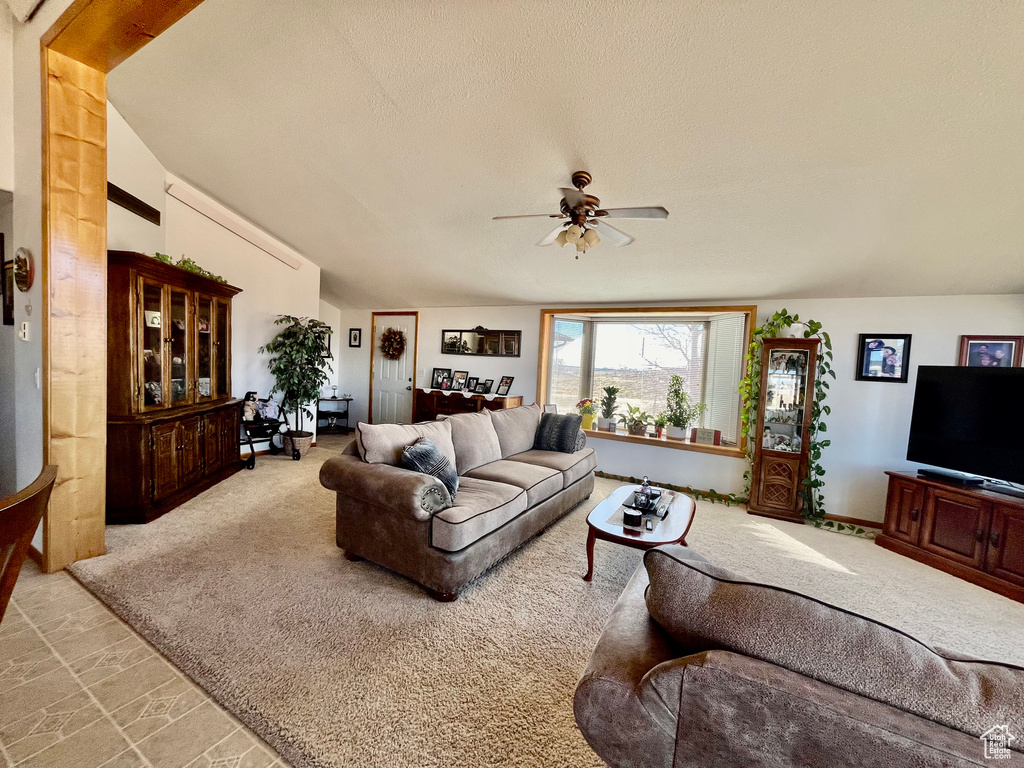 Living room featuring light carpet, vaulted ceiling, a textured ceiling, and ceiling fan