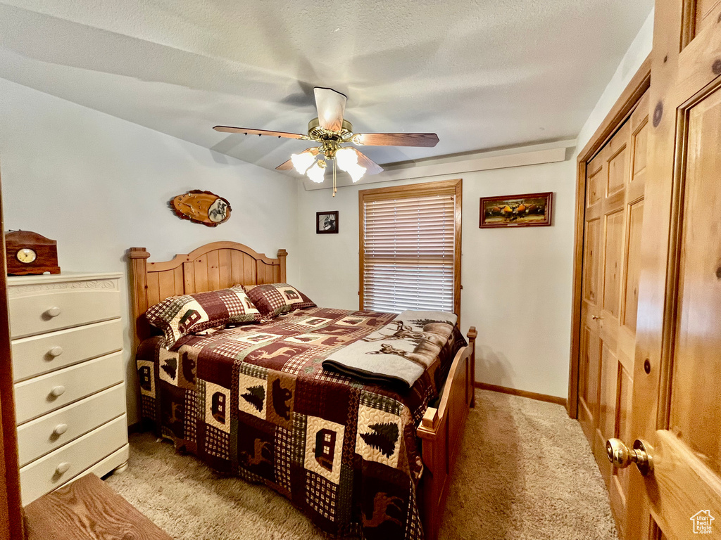 Carpeted bedroom with a closet, ceiling fan, and a textured ceiling