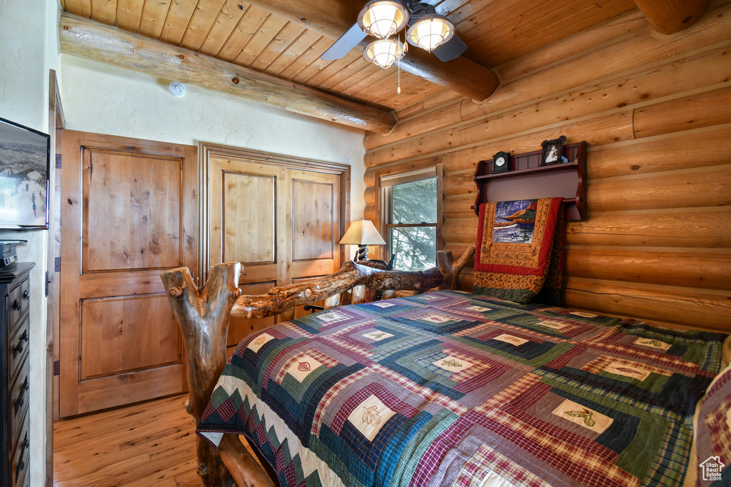Bedroom featuring log walls, wood ceiling, hardwood / wood-style flooring, and beam ceiling