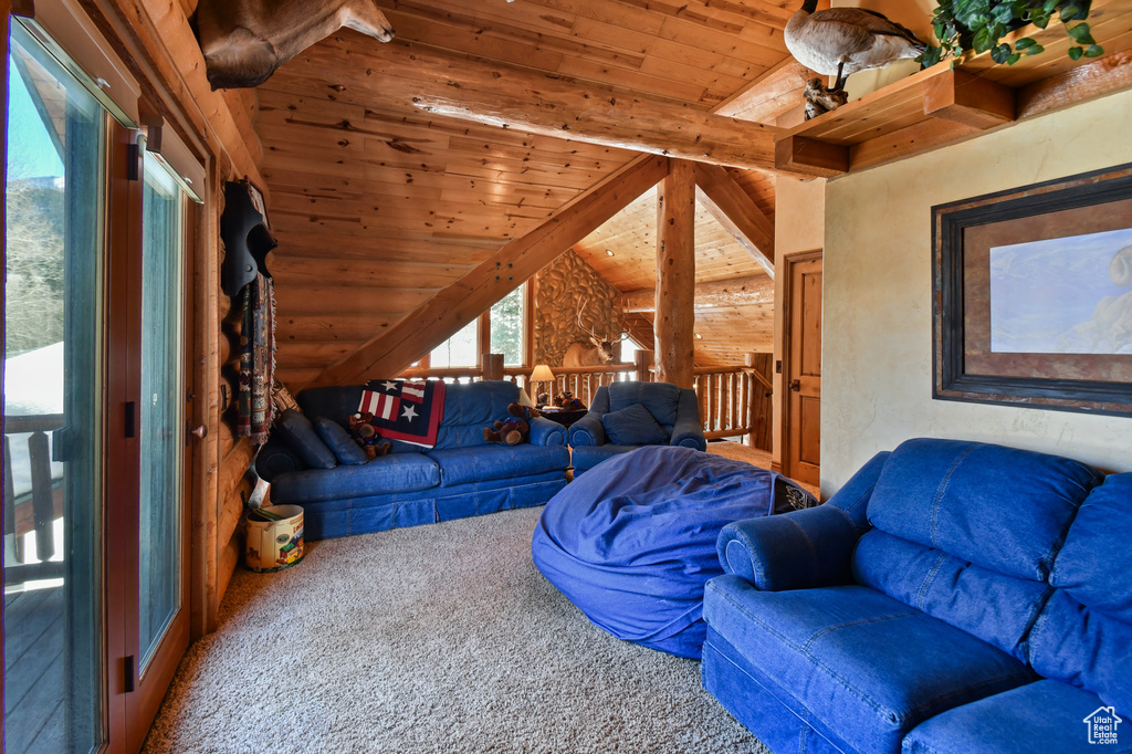 Living room with lofted ceiling with beams, log walls, carpet floors, and wooden ceiling