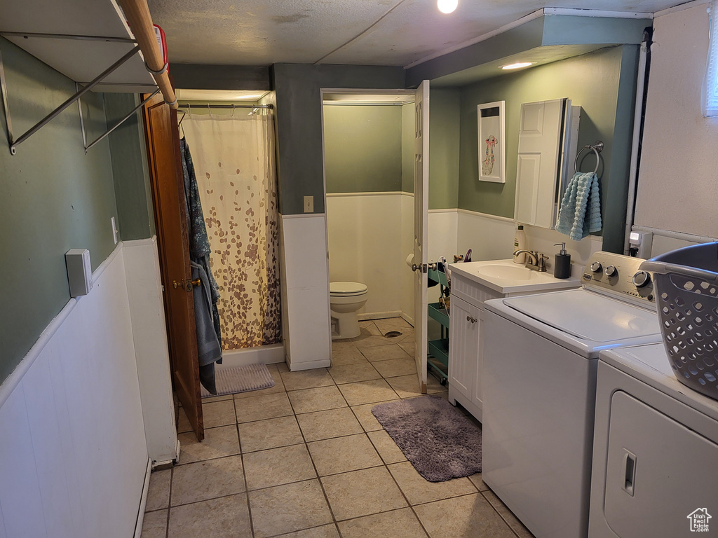 Laundry area with washer and dryer, light tile floors, and sink