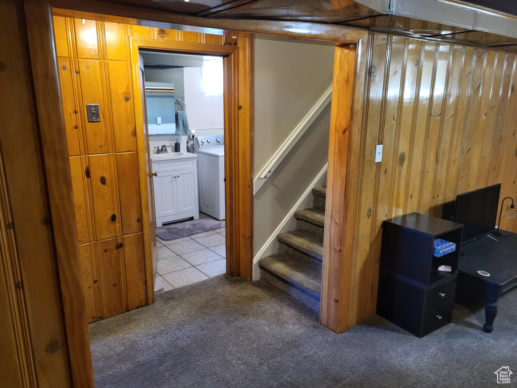 Basement with washer / dryer, light carpet, and wood walls