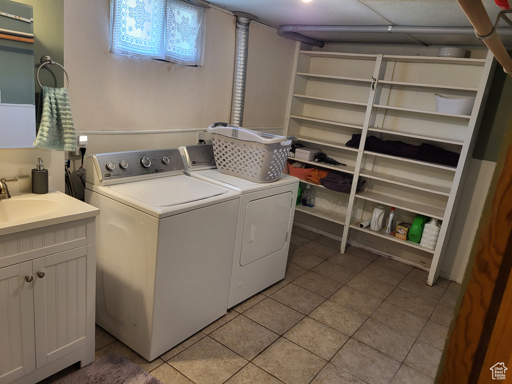 Laundry area with cabinets, separate washer and dryer, sink, and light tile floors