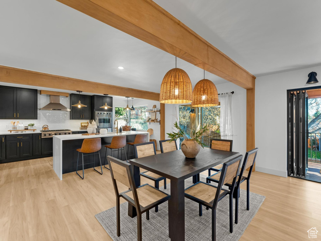 Dining area featuring beam ceiling, a wealth of natural light, and light hardwood / wood-style floors