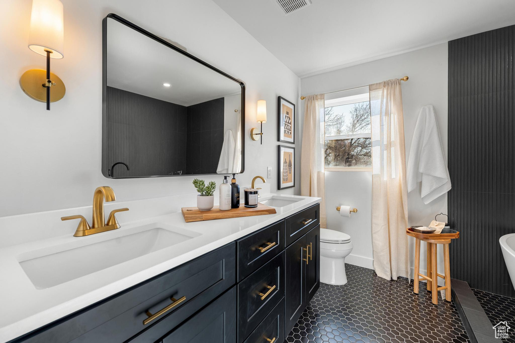 Bathroom featuring double sink vanity, toilet, and tile floors