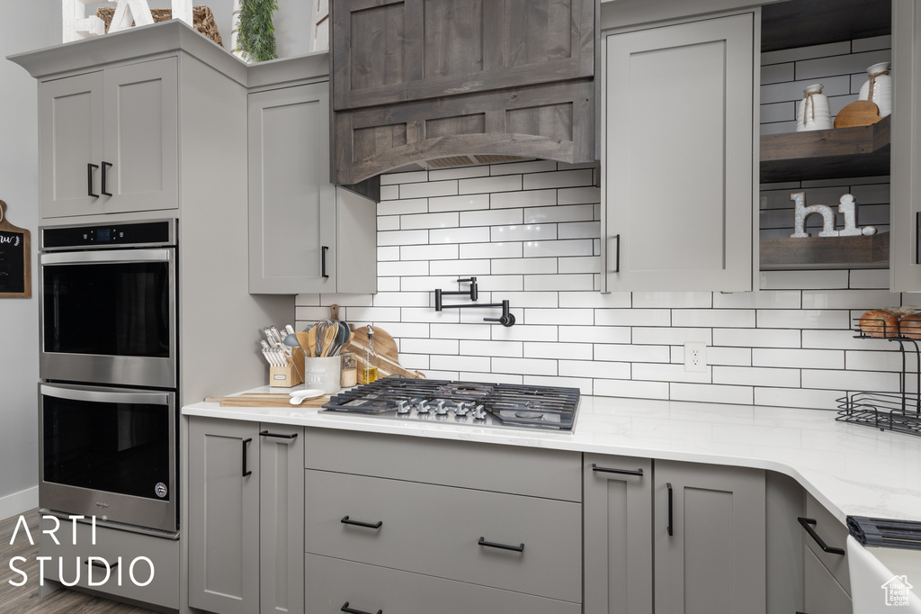 Kitchen featuring backsplash, stainless steel appliances, and gray cabinets