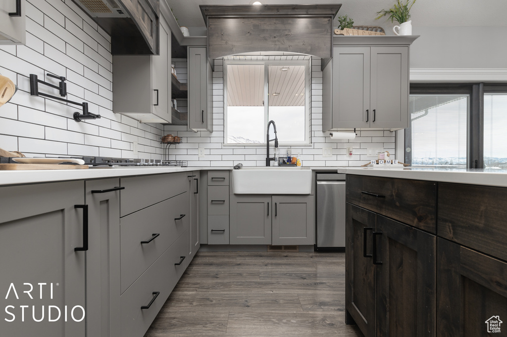 Kitchen featuring dark hardwood / wood-style flooring, tasteful backsplash, gray cabinets, dishwasher, and sink