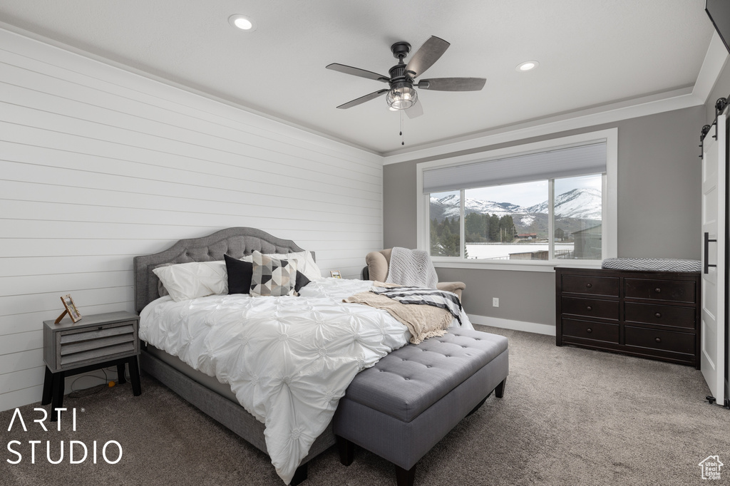 Bedroom featuring light carpet, a barn door, crown molding, a mountain view, and ceiling fan