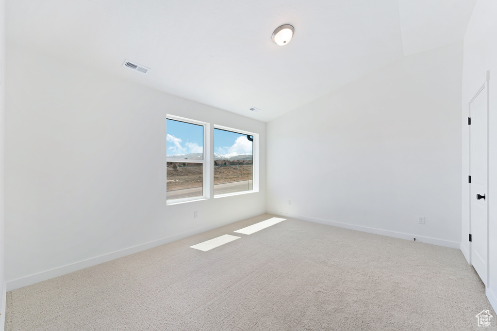 Carpeted empty room featuring lofted ceiling