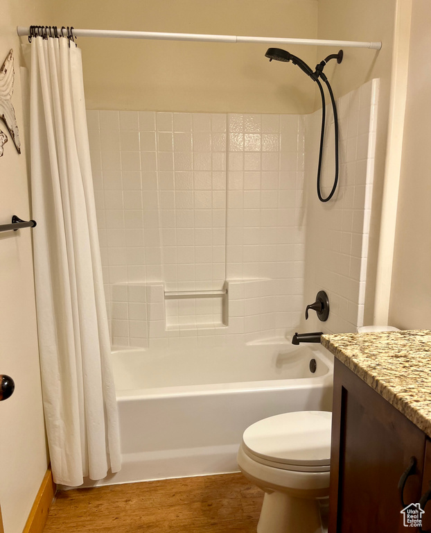 Full bathroom featuring wood-type flooring, shower / bathtub combination with curtain, and toilet
