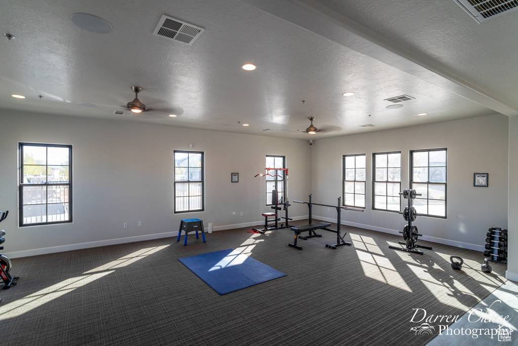 Workout room with a textured ceiling, ceiling fan, and light carpet