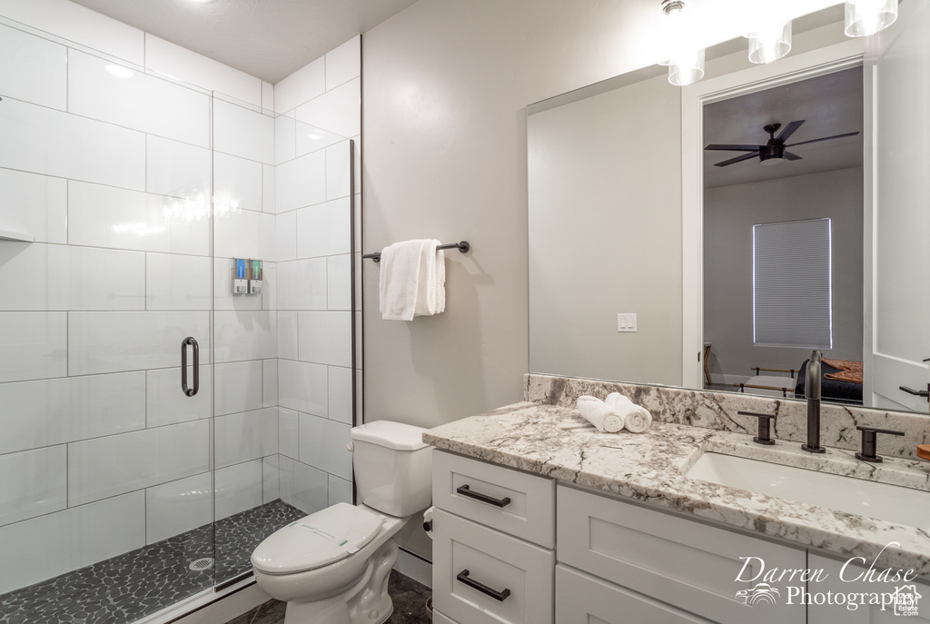 Bathroom featuring vanity with extensive cabinet space, an enclosed shower, toilet, and ceiling fan