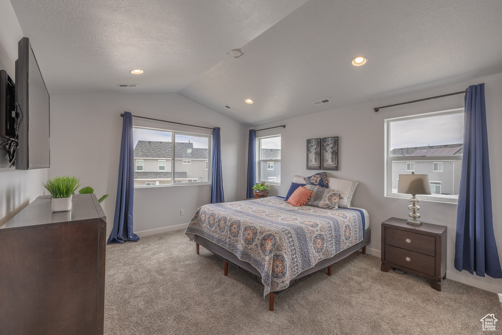 Bedroom featuring a textured ceiling, light carpet, and vaulted ceiling