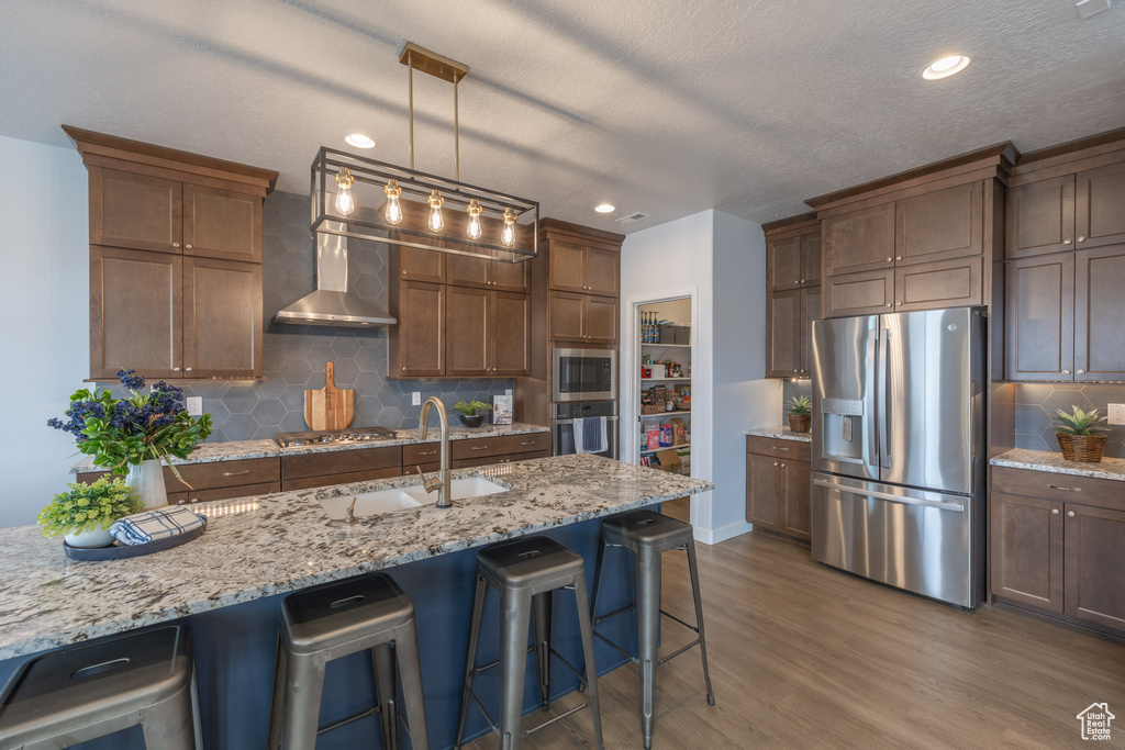 Kitchen with backsplash, a kitchen breakfast bar, stainless steel appliances, and dark hardwood / wood-style flooring
