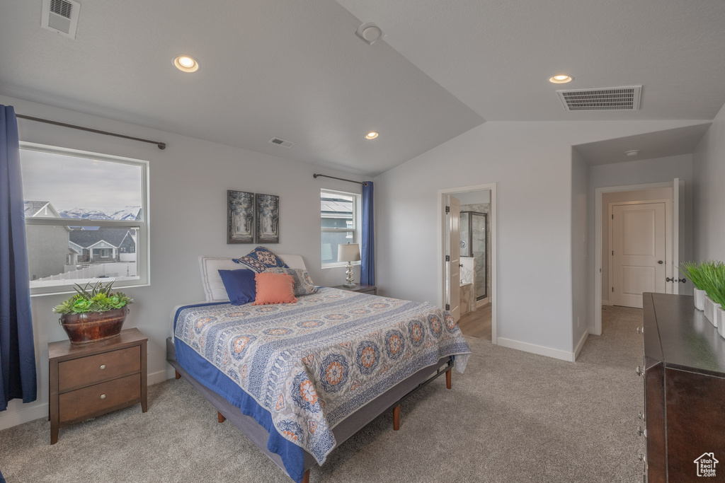 Bedroom with connected bathroom, vaulted ceiling, and light colored carpet