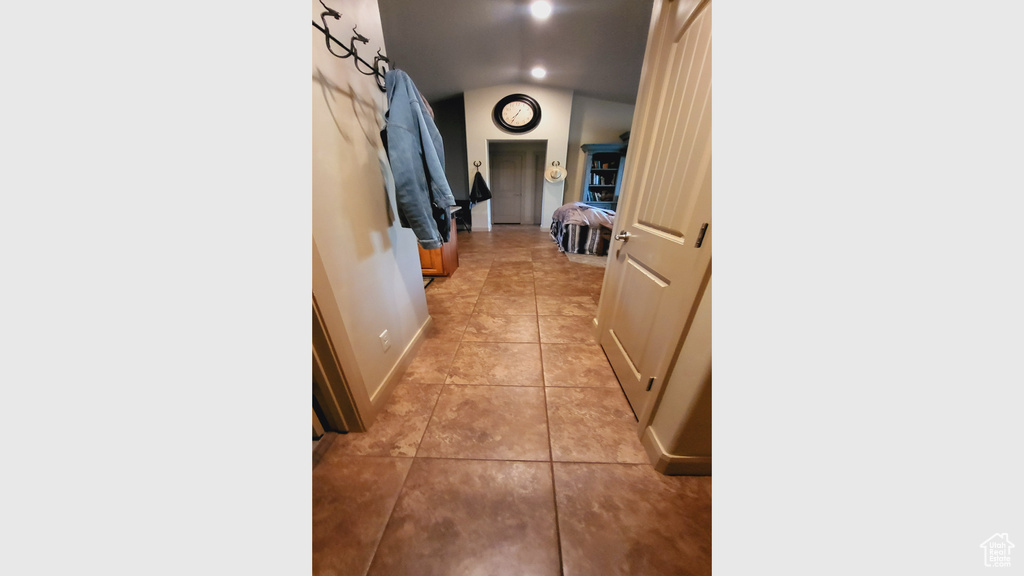 Hallway featuring lofted ceiling and light tile floors
