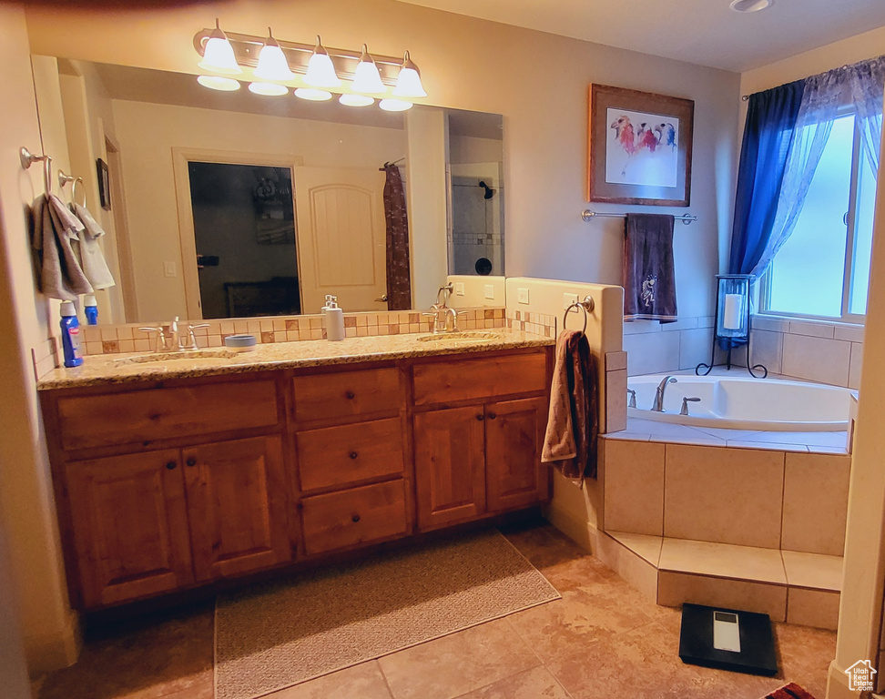Bathroom featuring dual vanity, tile flooring, and tiled bath