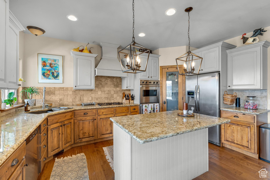 Kitchen with a center island, tasteful backsplash, white cabinetry, custom range hood, and dark hardwood / wood-style flooring