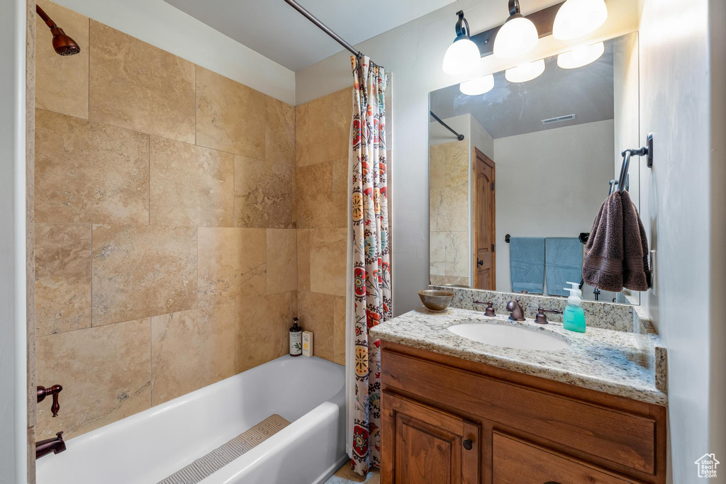 Bathroom featuring vanity with extensive cabinet space and shower / bathtub combination with curtain