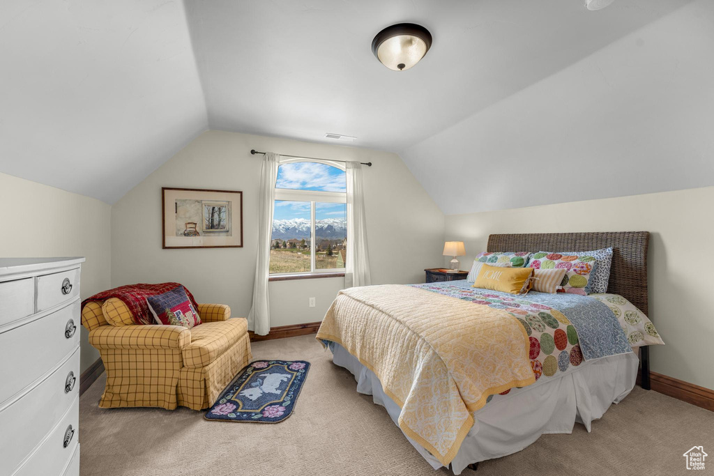 Bedroom with light carpet and lofted ceiling
