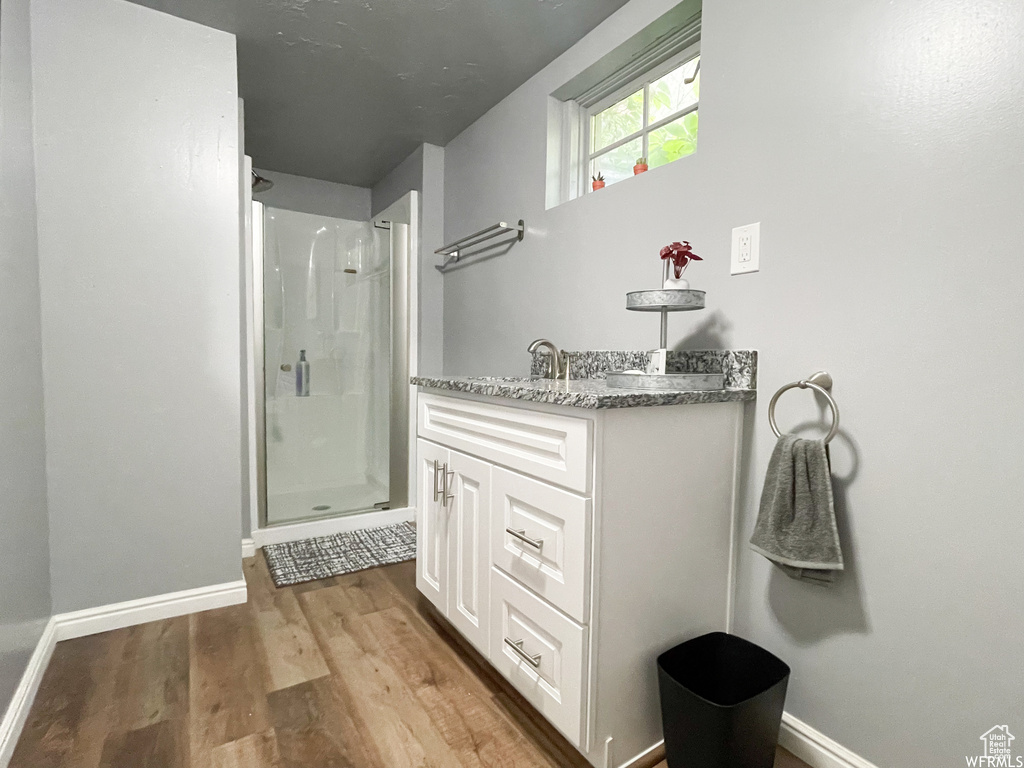Bathroom featuring vanity, hardwood / wood-style floors, and a shower with shower door