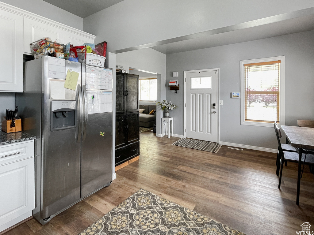 Kitchen featuring white cabinetry, a healthy amount of sunlight, dark hardwood / wood-style floors, and stainless steel refrigerator with ice dispenser