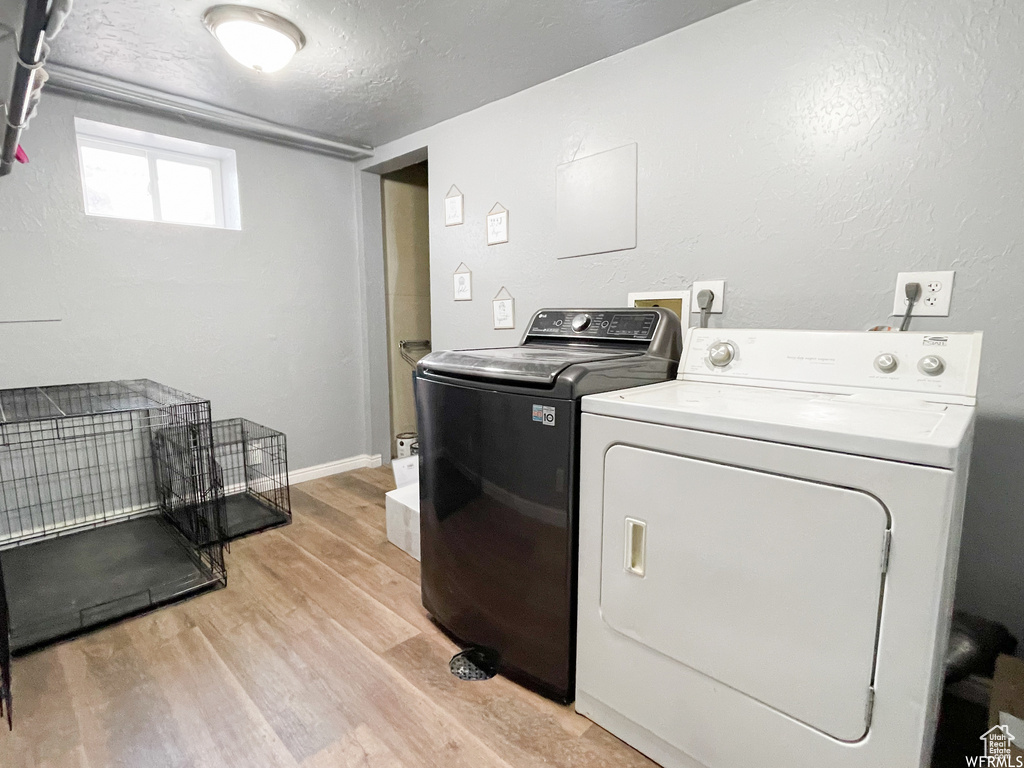 Laundry room with hookup for an electric dryer, hookup for a washing machine, light hardwood / wood-style flooring, a textured ceiling, and separate washer and dryer