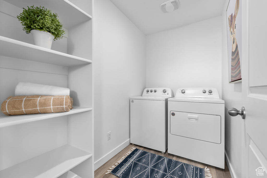 Clothes washing area with separate washer and dryer and dark wood-type flooring