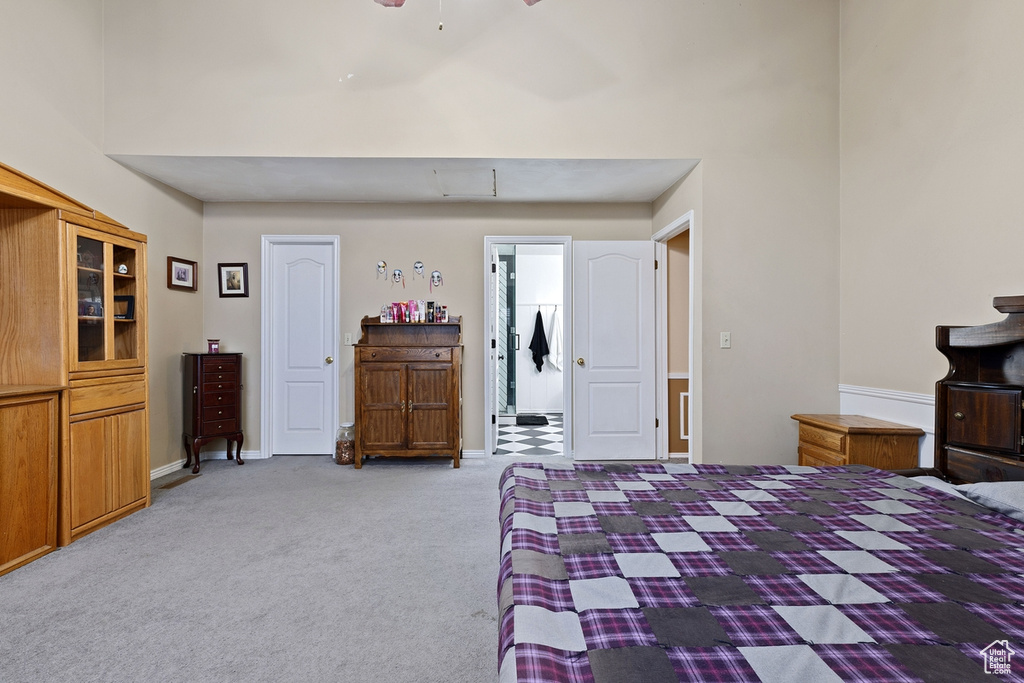 Bedroom featuring light carpet and a towering ceiling