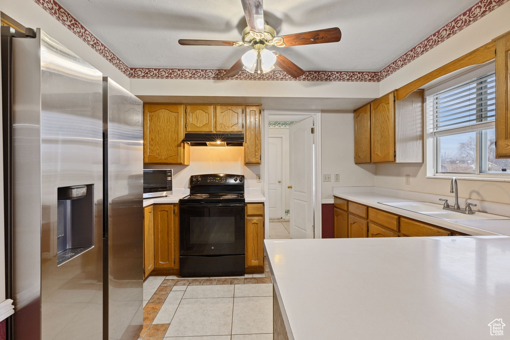 Kitchen featuring light tile flooring, ceiling fan, appliances with stainless steel finishes, and sink