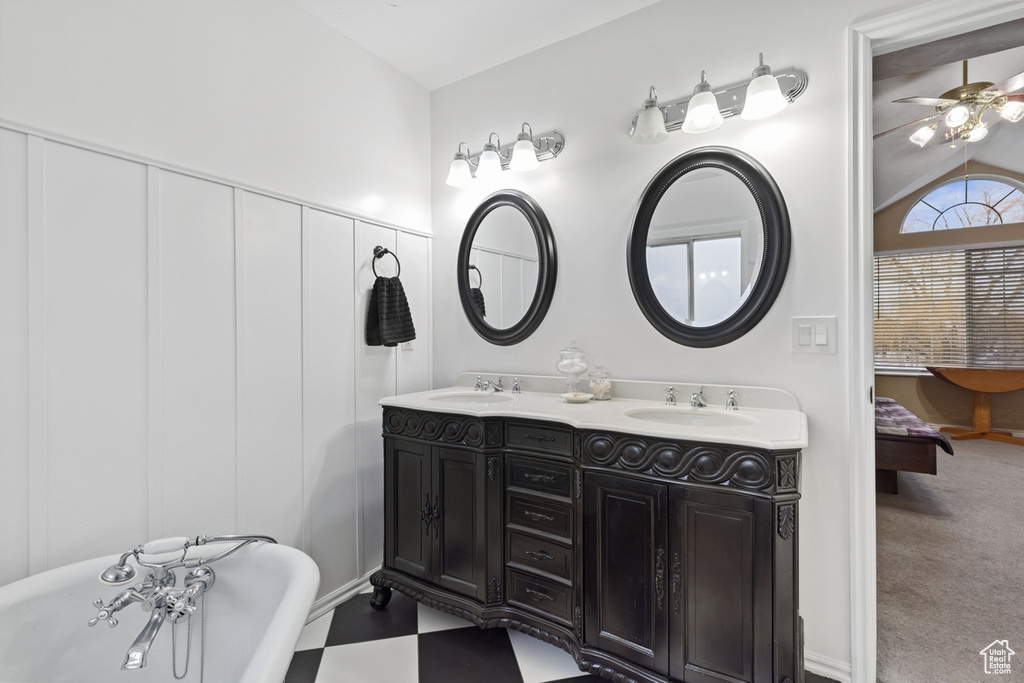 Bathroom featuring double sink, ceiling fan, vaulted ceiling, a tub, and oversized vanity