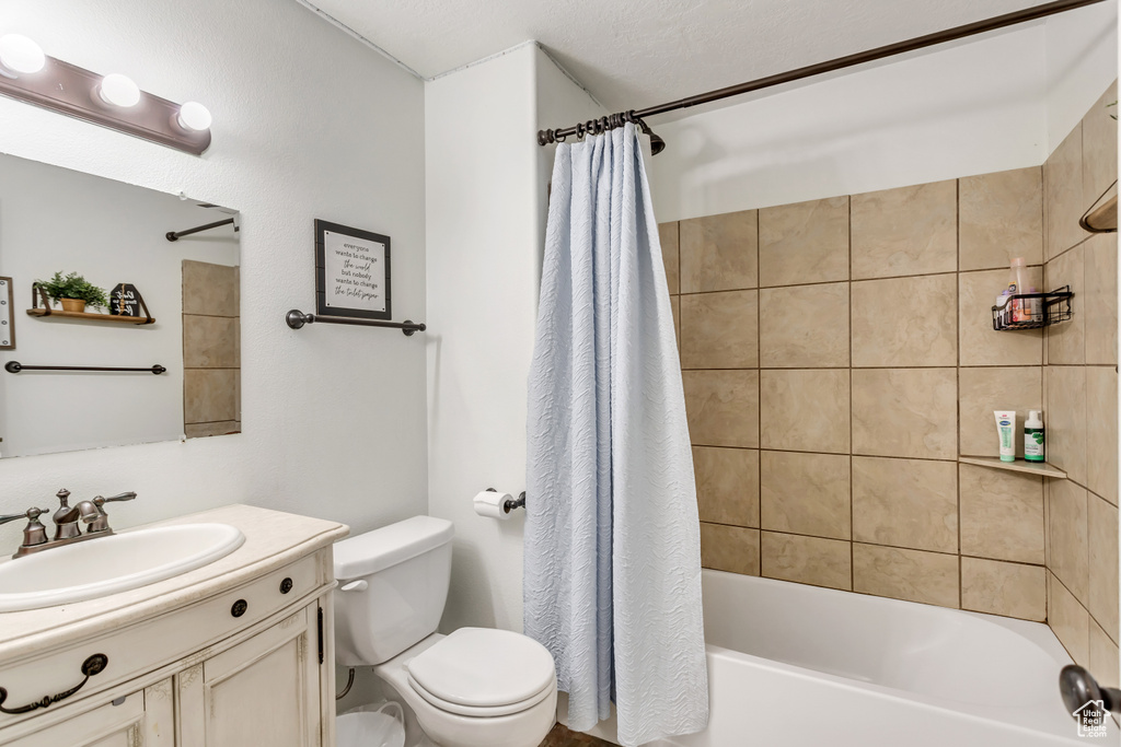 Full bathroom featuring shower / bath combo, toilet, a textured ceiling, and vanity
