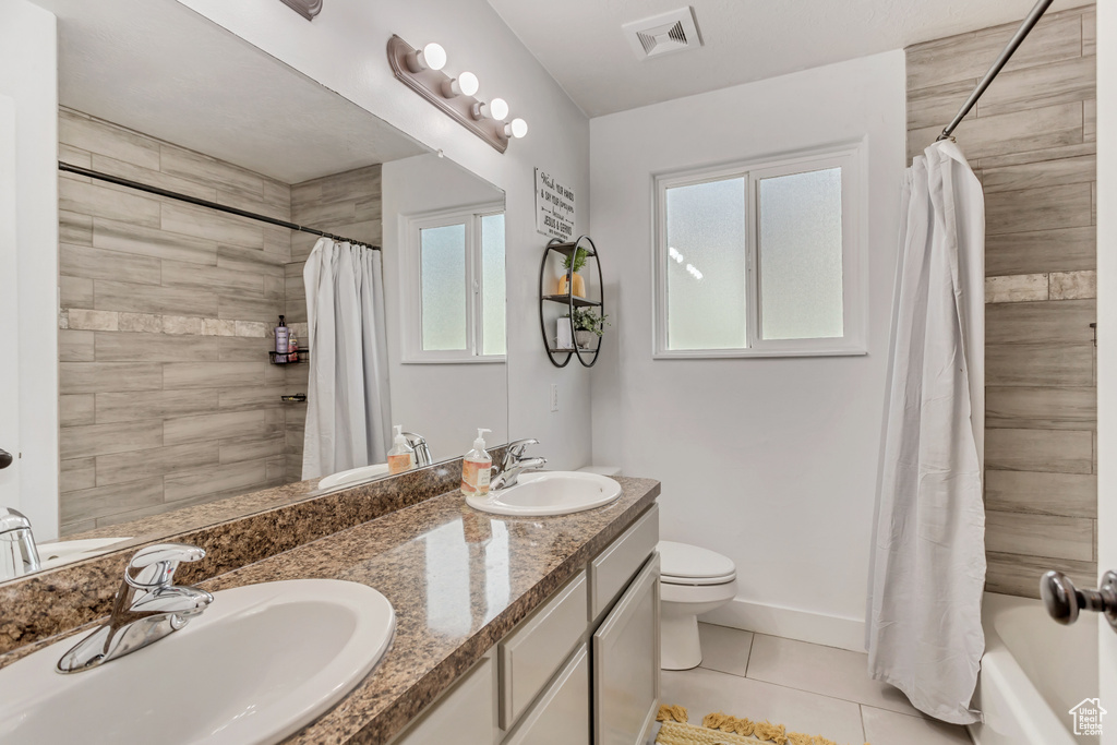 Full bathroom featuring shower / bath combo with shower curtain, toilet, dual bowl vanity, and tile flooring