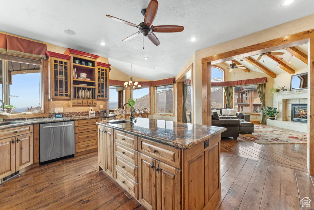 Kitchen with dark hardwood / wood-style flooring, vaulted ceiling with beams, stainless steel dishwasher, ceiling fan with notable chandelier, and sink