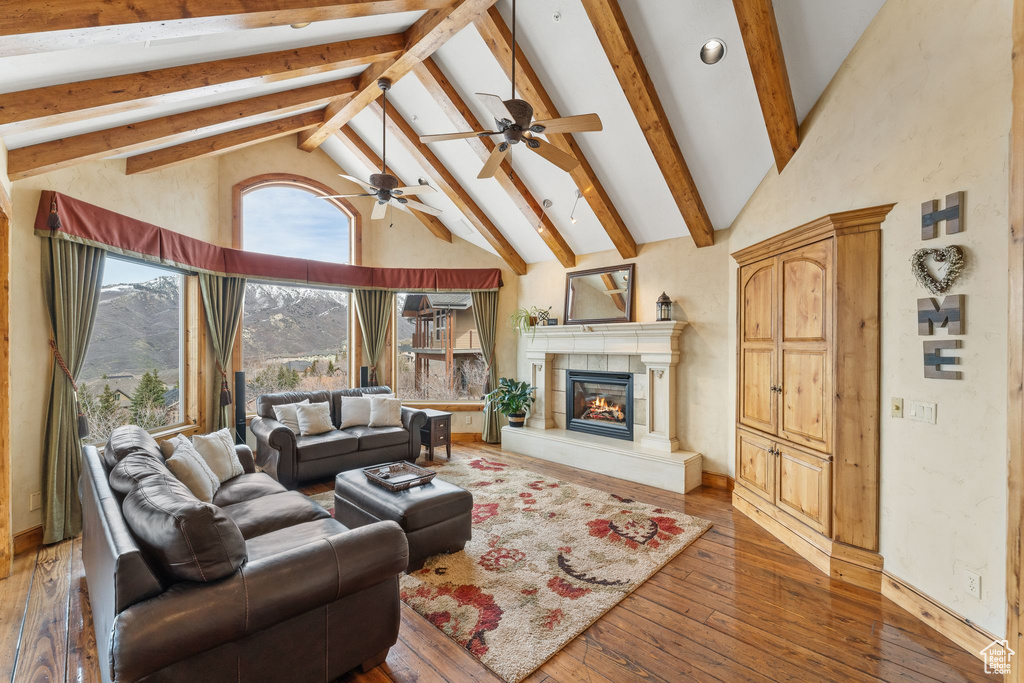 Living room with dark hardwood / wood-style flooring, ceiling fan, beamed ceiling, and high vaulted ceiling