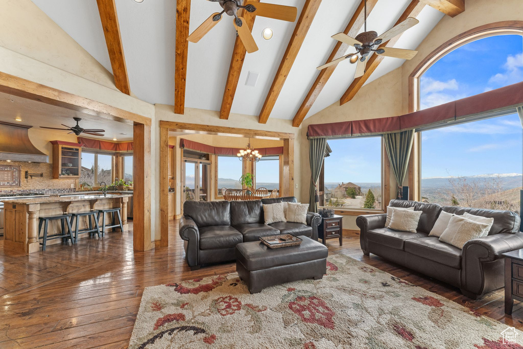 Living room with plenty of natural light, dark hardwood / wood-style flooring, and ceiling fan with notable chandelier
