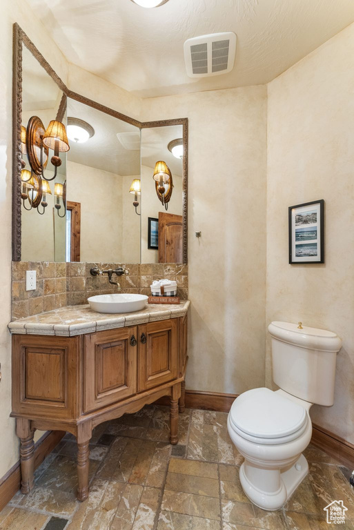 Bathroom featuring backsplash, toilet, tile floors, and vanity with extensive cabinet space