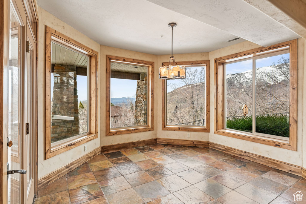Unfurnished sunroom featuring a chandelier and a mountain view