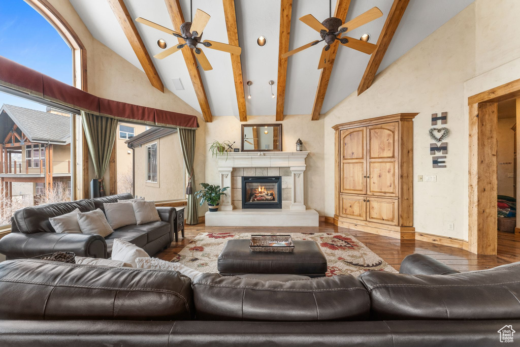 Living room featuring beam ceiling, high vaulted ceiling, light hardwood / wood-style floors, and ceiling fan