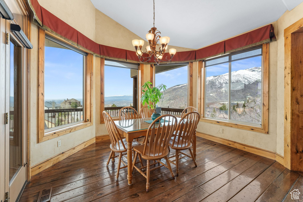 Dining space with a notable chandelier, dark hardwood / wood-style floors, a wealth of natural light, and a mountain view