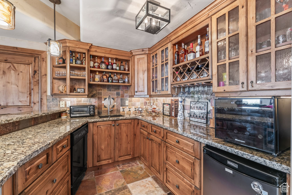 Kitchen featuring light stone countertops, tile floors, sink, dishwasher, and pendant lighting