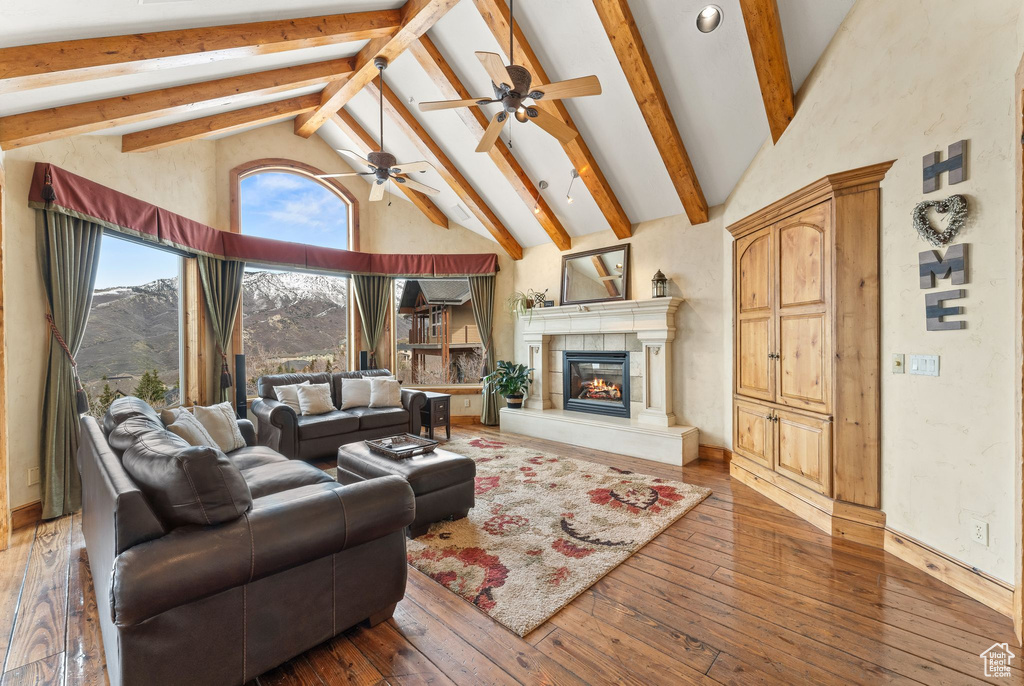 Living room featuring high vaulted ceiling, beam ceiling, dark hardwood / wood-style flooring, and ceiling fan