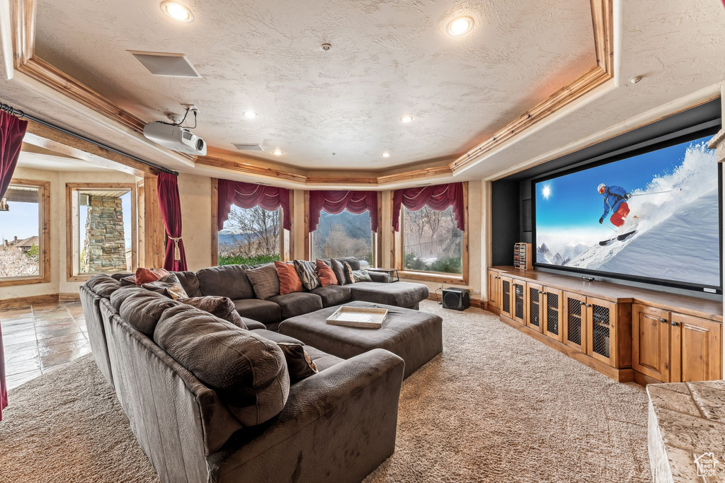 Home theater room featuring light tile flooring, a tray ceiling, and ornamental molding