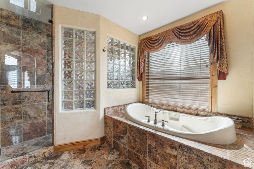 Bathroom featuring plenty of natural light, tile flooring, and plus walk in shower
