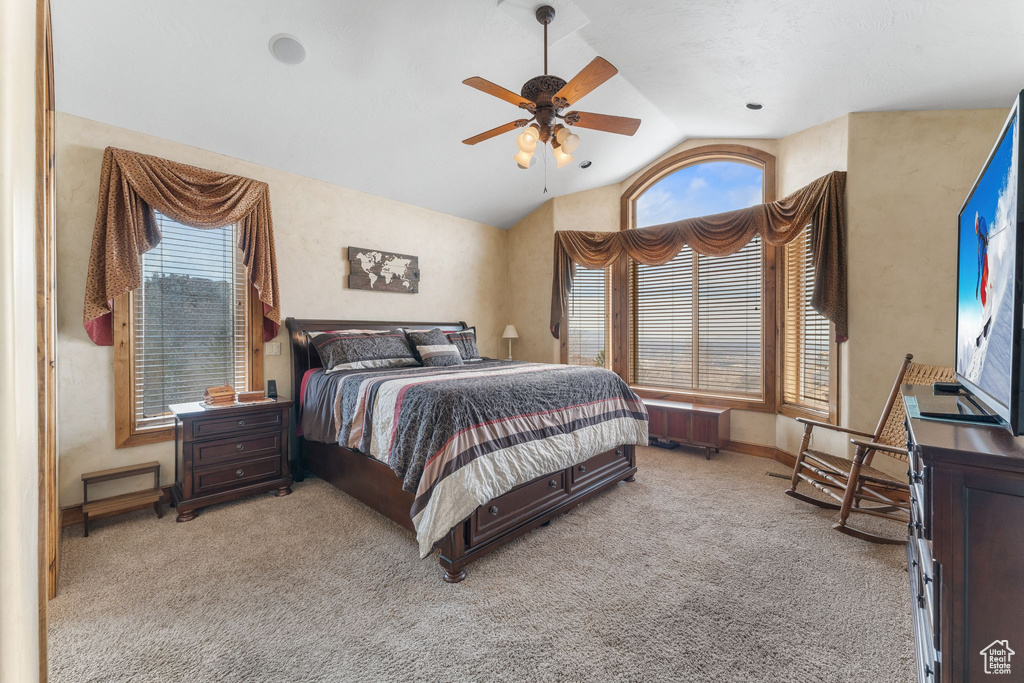 Carpeted bedroom featuring ceiling fan, radiator heating unit, and lofted ceiling